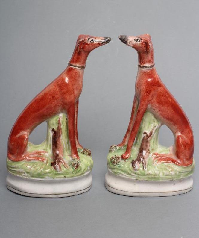 A PAIR OF LATE VICTORIAN STAFFORDSHIRE POTTERY SEATED GREYHOUNDS with free standing fore-legs and Image