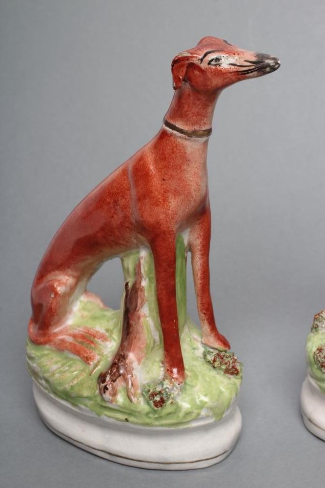 A PAIR OF LATE VICTORIAN STAFFORDSHIRE POTTERY SEATED GREYHOUNDS with free standing fore-legs and Image
