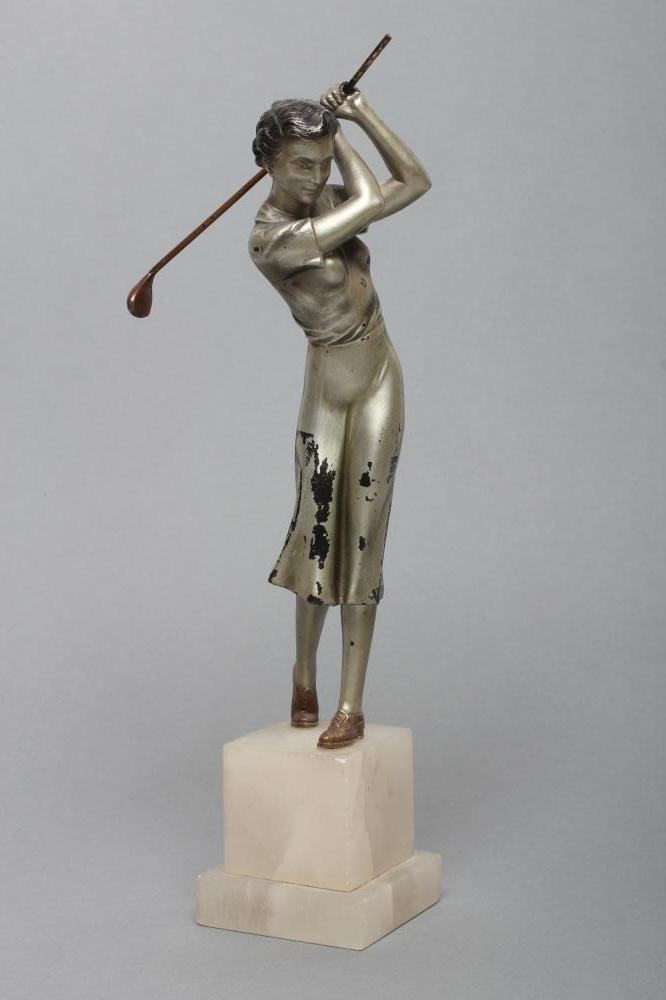 AN ART DECO SILVERED SPELTER LADY GOLFER FIGURE standing on a stepped white onyx base Image