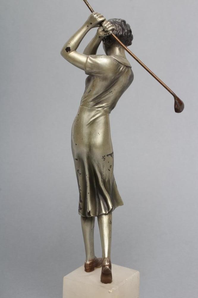 AN ART DECO SILVERED SPELTER LADY GOLFER FIGURE standing on a stepped white onyx base Image