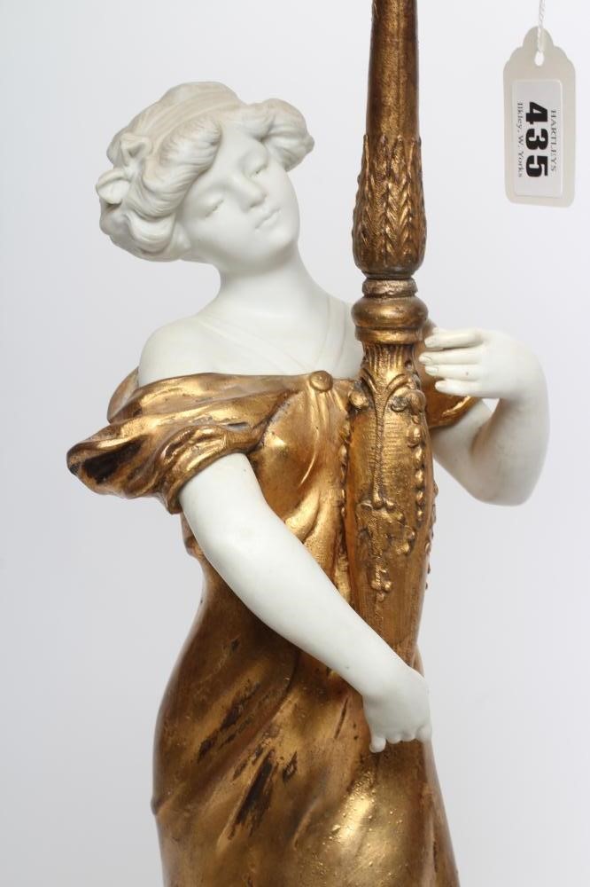 A FRENCH GILDED BRONZE AND BISQUE FIGURAL TABLE LAMP modelled as an Art Nouveau style maiden Image