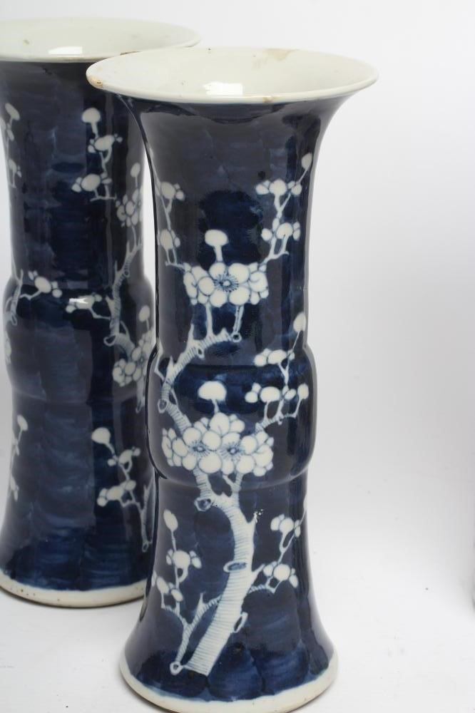 A PAIR OF CHINESE PORCELAIN GU VASES painted in underglaze blue with prunus on a dark shaded ground Image