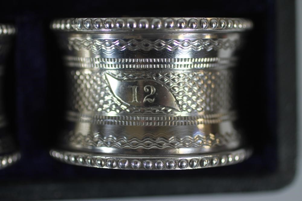 A SET OF TWELVE LATE VICTORIAN EPNS NAPKIN RINGS of waisted cylindrical form with bead cast borders Image
