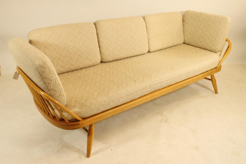AN ERCOL BEECH AND ELM STUDIO COUCH of rounded oblong form with raised solid back and hooped ends on Image