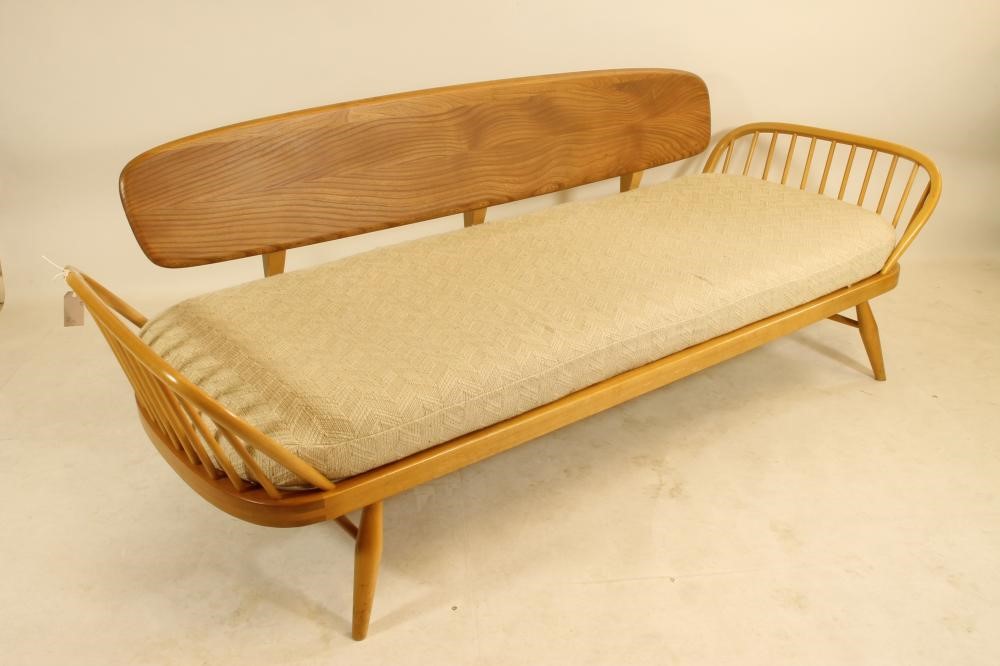 AN ERCOL BEECH AND ELM STUDIO COUCH of rounded oblong form with raised solid back and hooped ends on Image
