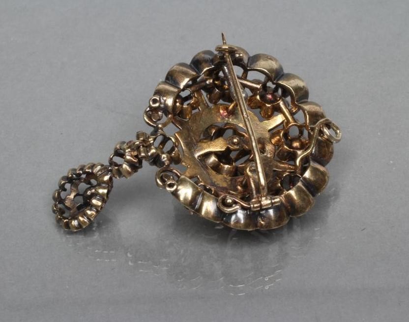 A VICTORIAN DIAMOND PENDANT/BROOCH claw set with eleven old mine cut stones within an unmarked black Image