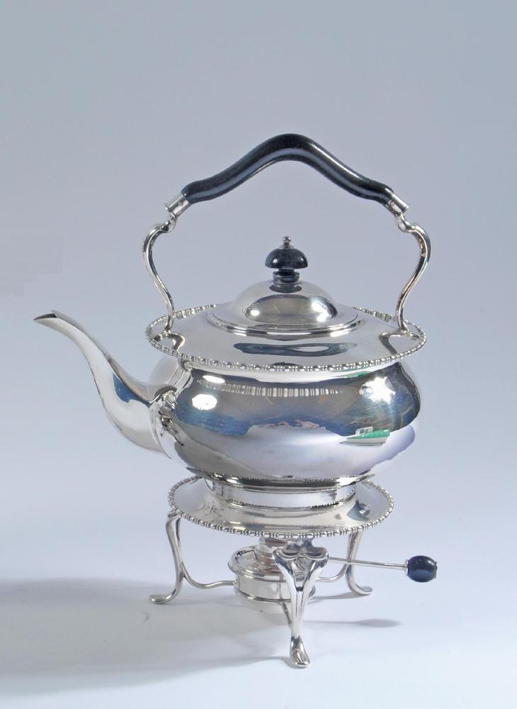 A SILVER TEA KETTLE AND BURNER ON STAND Image