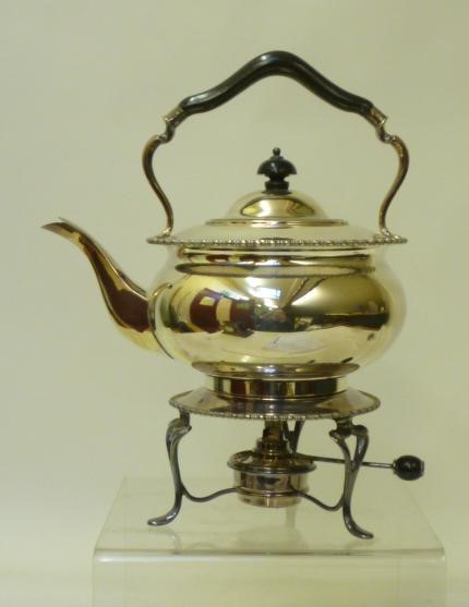 A SILVER TEA KETTLE AND BURNER ON STAND Image