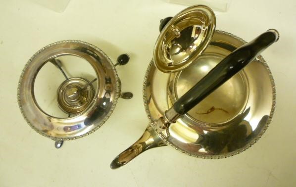 A SILVER TEA KETTLE AND BURNER ON STAND Image