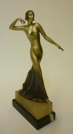 AN ART DECO SILVERED AND BRONZED SPELTER FIGURE of a young female dancer wearing a long flowing Image