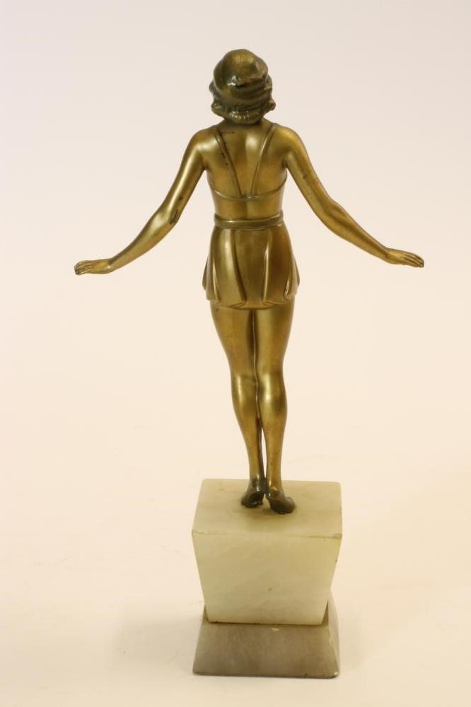 AN ART DECO BRONZED SPELTER FIGURE of a young girl wearing a bathing costume with belted skirt Image