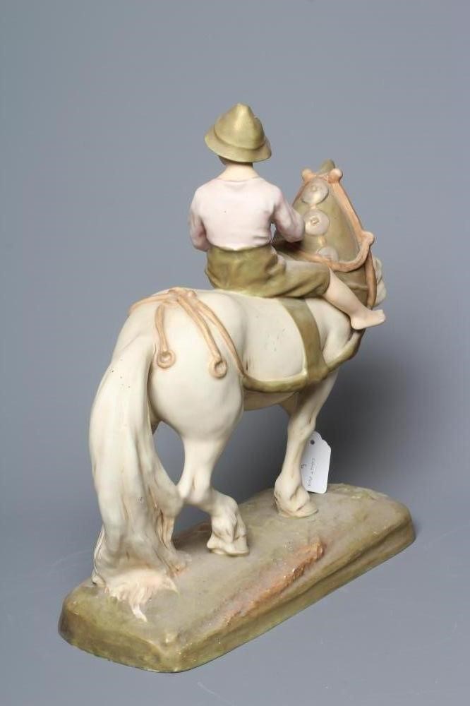 A ROYAL DUX SHIRE HORSE in harness and with a young boy in traditional garb seated astride, on a Image