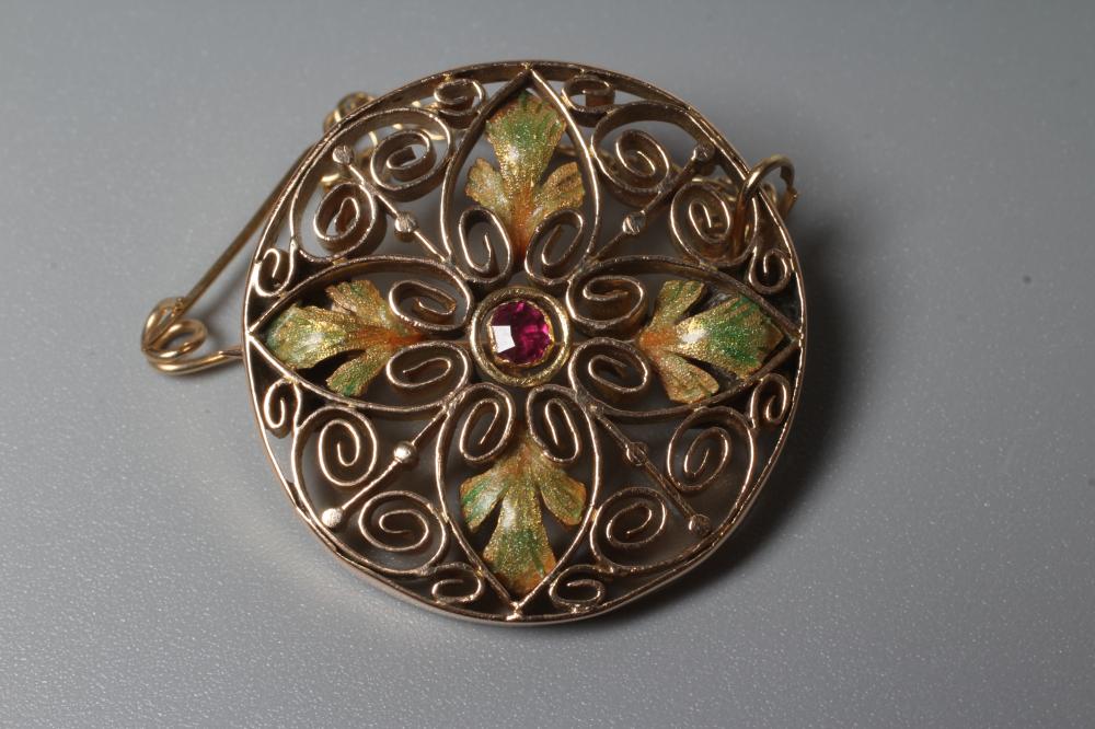 AN ARTS AND CRAFTS CIRCULAR BROOCH of open flowerhead design centred by a cushion cut ruby in Image