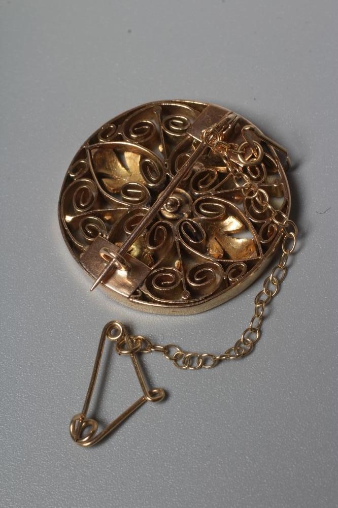 AN ARTS AND CRAFTS CIRCULAR BROOCH of open flowerhead design centred by a cushion cut ruby in Image