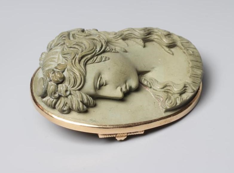 A VICTORIAN OVAL LAVA BROOCH carved in high relief with the head and shoulders portrait of the Greek Image