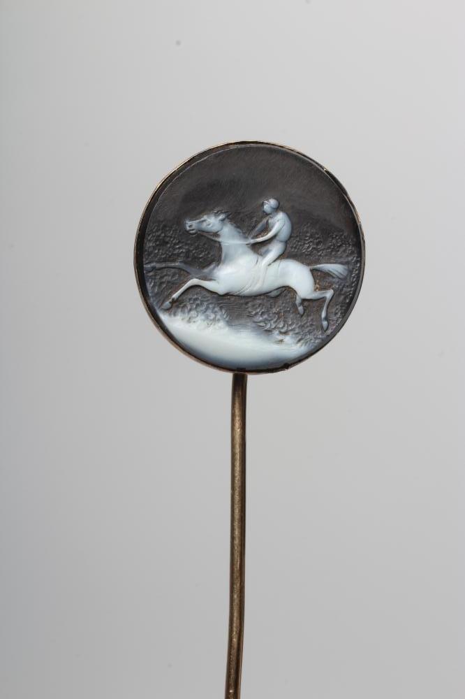 AN EARLY VICTORIAN STOCK PIN, the circular black and white agate panel cameo cut with a race horse Image
