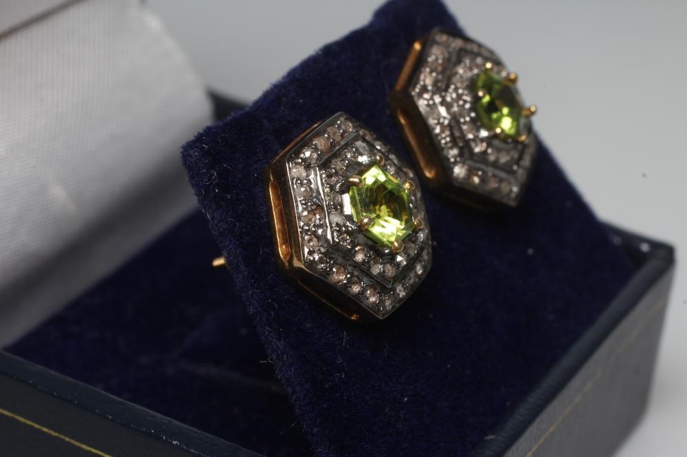 A PAIR OF PERIDOT AND DIAMOND EAR STUDS, the hexagonal cut peridots claw set to two rows of rose cut Image