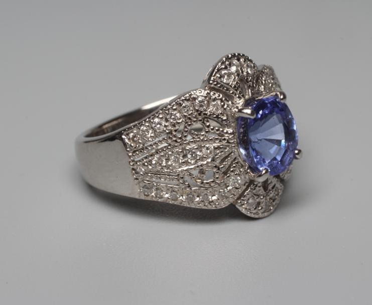A TANZANITE AND DIAMOND COCKTAIL RING, the oval tanzanite claw set to borders pierced and set with Image