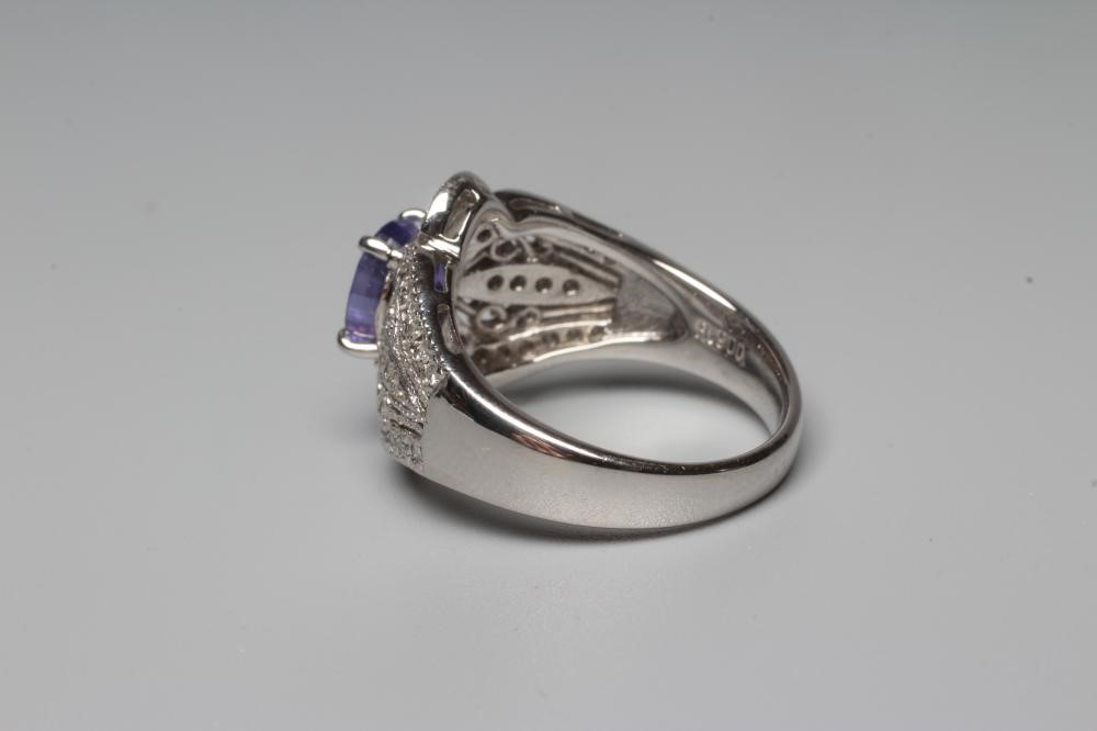 A TANZANITE AND DIAMOND COCKTAIL RING, the oval tanzanite claw set to borders pierced and set with Image