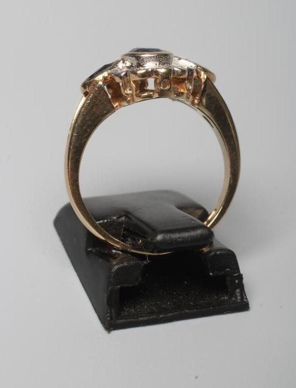 A SAPPHIRE AND DIAMOND CLUSTER RING, the central oval facet cut sapphire in rub over setting within Image