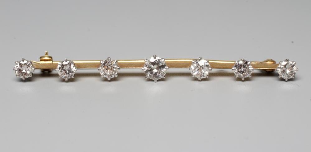 A SEVEN STONE DIAMOND BAR BROOCH, the central brilliant cut stone of approximately 0.75cts flanked Image