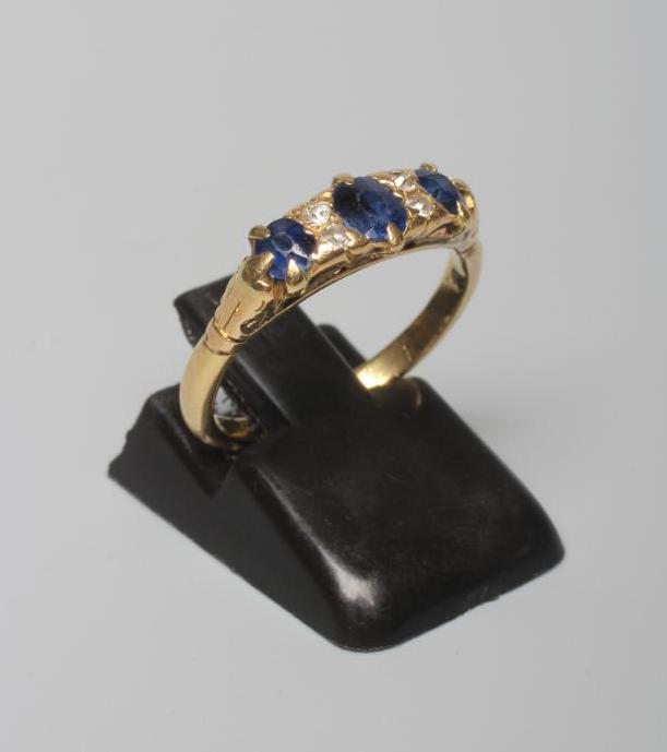 A SAPPHIRE AND DIAMOND HALF HOOP RING set with three facet cut sapphires with diamond points between Image