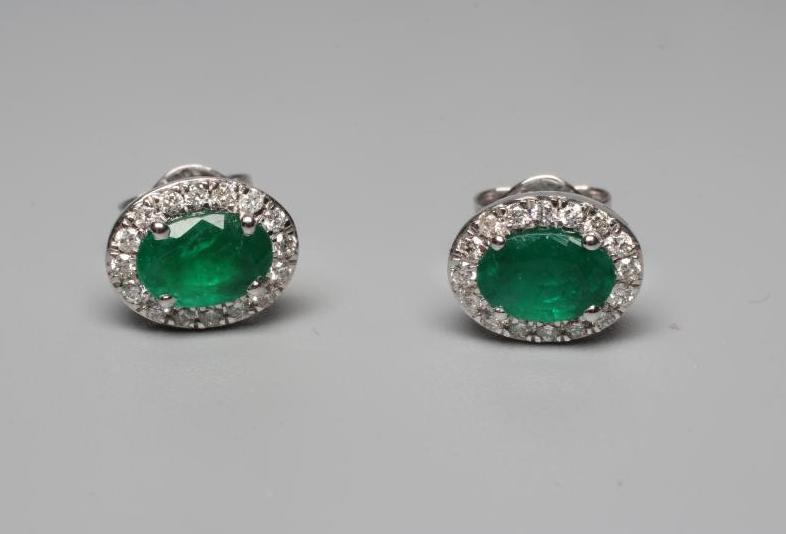 A PAIR OF EMERALD AND DIAMOND CLUSTER EAR STUDS, the oval facet cut emeralds claw set to a border of Image