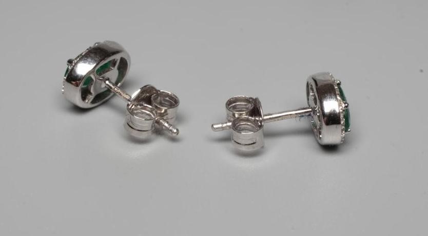 A PAIR OF EMERALD AND DIAMOND CLUSTER EAR STUDS, the oval facet cut emeralds claw set to a border of Image