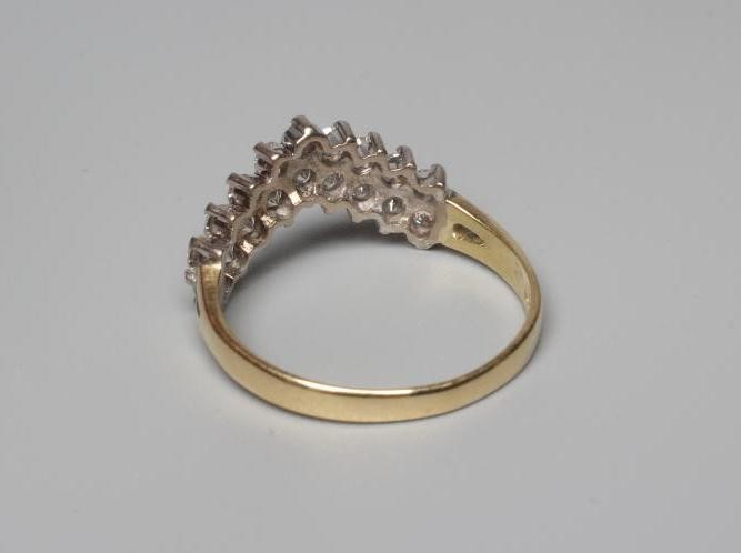 A DIAMOND WISHBONE RING claw set with nine pairs of round brilliant cut stones to a plain 18ct gold Image