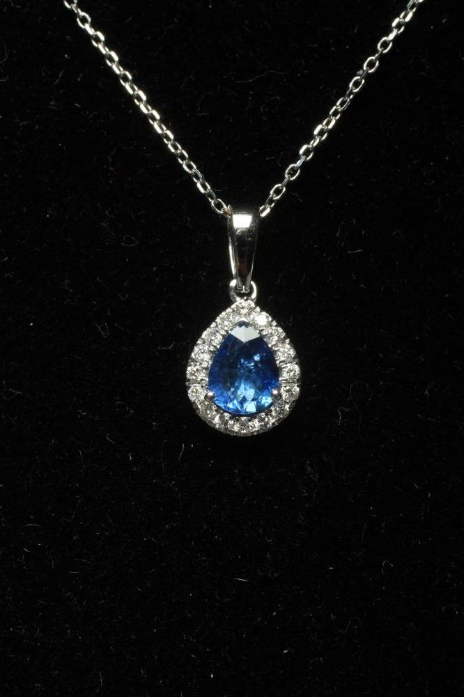 A SAPPHIRE AND DIAMOND CLUSTER PENDANT, the pear cut sapphire claw set to a border of round Image
