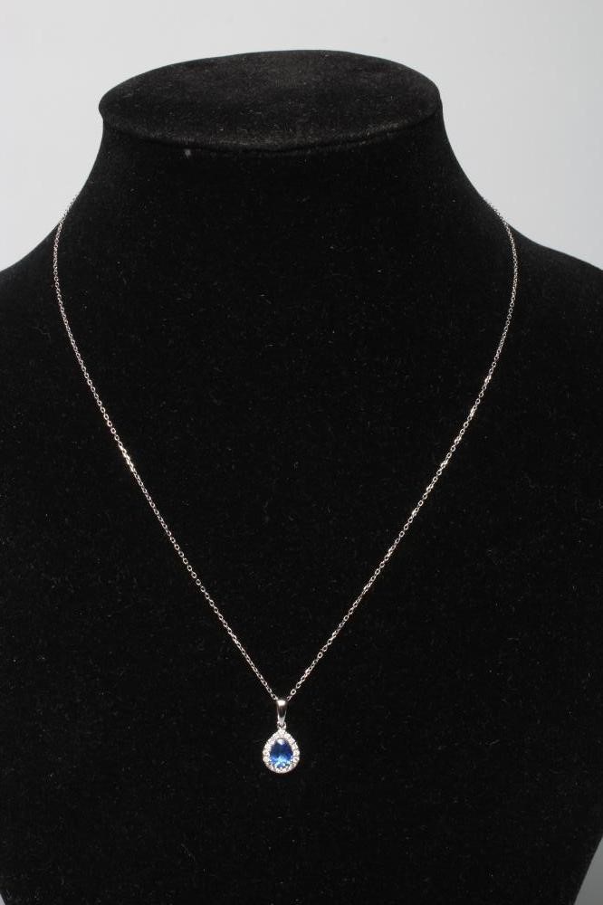 A SAPPHIRE AND DIAMOND CLUSTER PENDANT, the pear cut sapphire claw set to a border of round Image