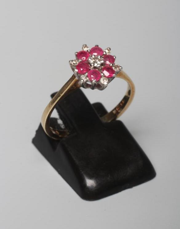 A RUBY AND DIAMOND CLUSTER RING, the central small diamond to a border of six round facet cut rubies Image