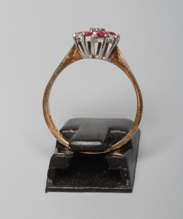 A RUBY AND DIAMOND CLUSTER RING, the central small diamond to a border of six round facet cut rubies Image