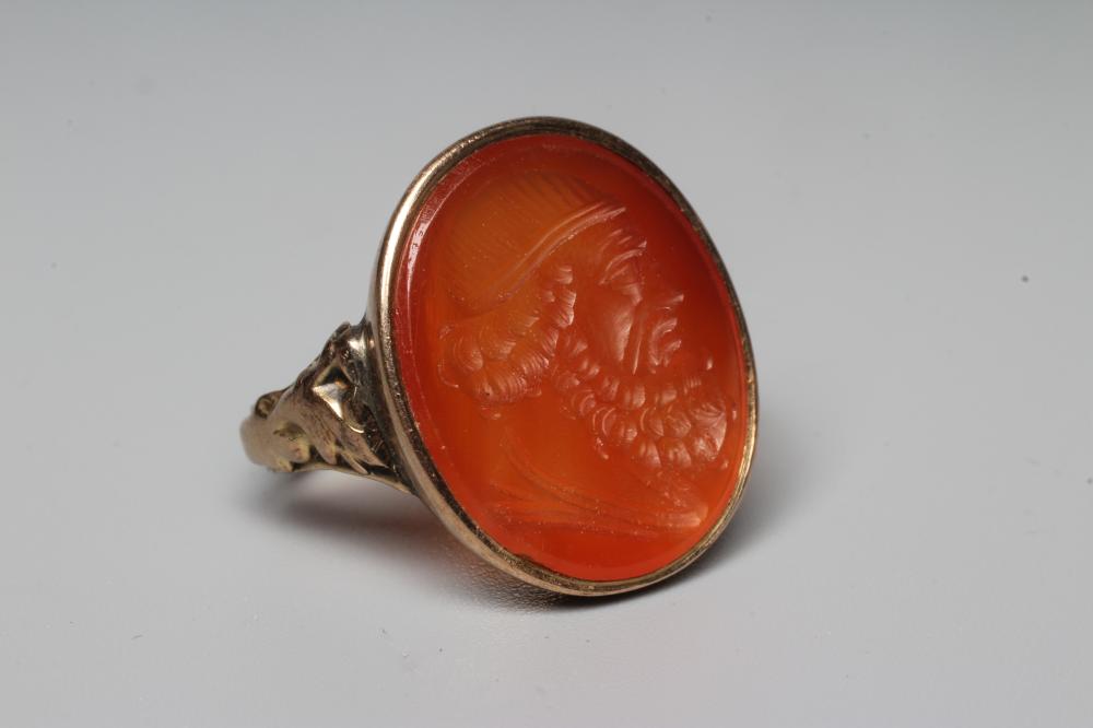 A LATE 18TH CENTURY SEAL RING, the oval cornelian incuse carved with a male head portrait, in a rub Image