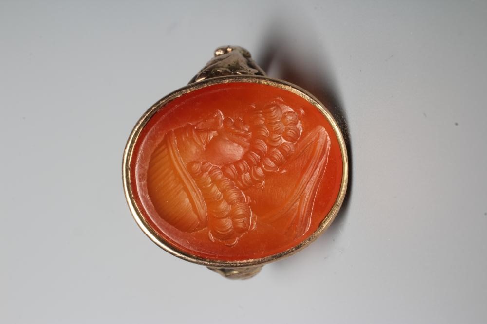 A LATE 18TH CENTURY SEAL RING, the oval cornelian incuse carved with a male head portrait, in a rub Image