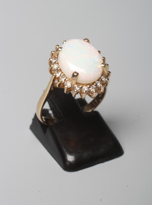 AN OPAL AND DIAMOND CLUSTER RING, the oval cabochon polished opal claw set to a border of round Image