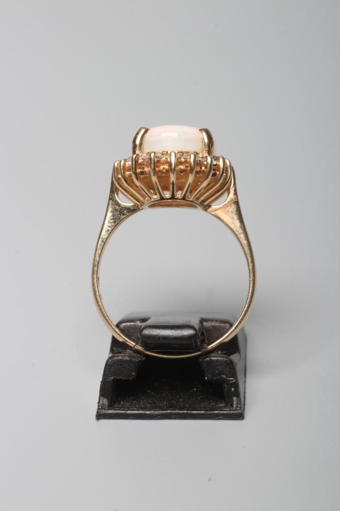 AN OPAL AND DIAMOND CLUSTER RING, the oval cabochon polished opal claw set to a border of round Image