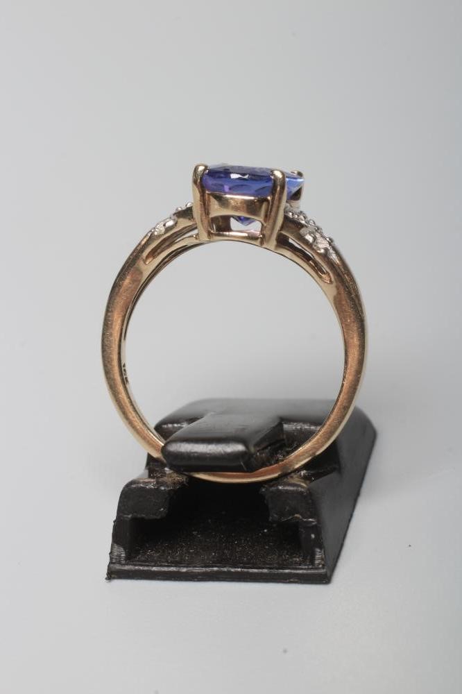 A TANZANITE DRESS RING, the oval facet cut stone claw set to reeded shoulders each pave set with six Image