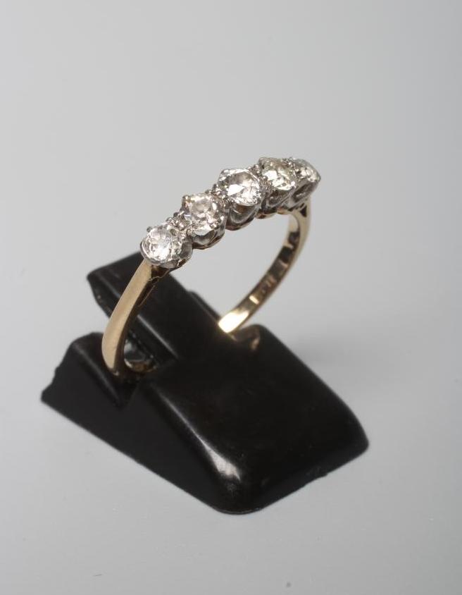 A FIVE STONE DIAMOND RING, the graduating brilliant cut stones claw set to a plain shank, stamped Image