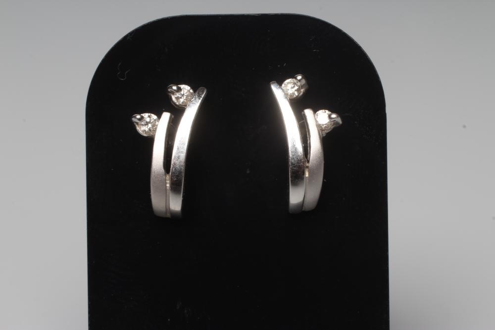 A PAIR OF DIAMOND EAR STUDS, each with a matt and polished S claw set with a small round brilliant Image