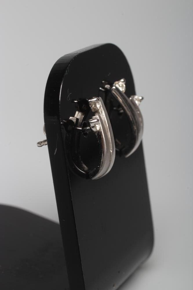 A PAIR OF DIAMOND EAR STUDS, each with a matt and polished S claw set with a small round brilliant Image