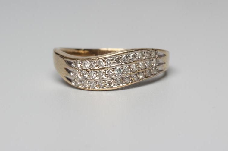 A DIAMOND DRESS RING, the wavy band point set with three bands of eleven stones to a plain shank Image
