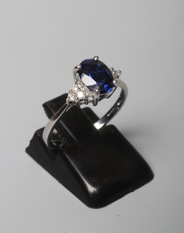A SAPPHIRE RING, the oval facet cut stone claw set to shoulders each set with three small round Image