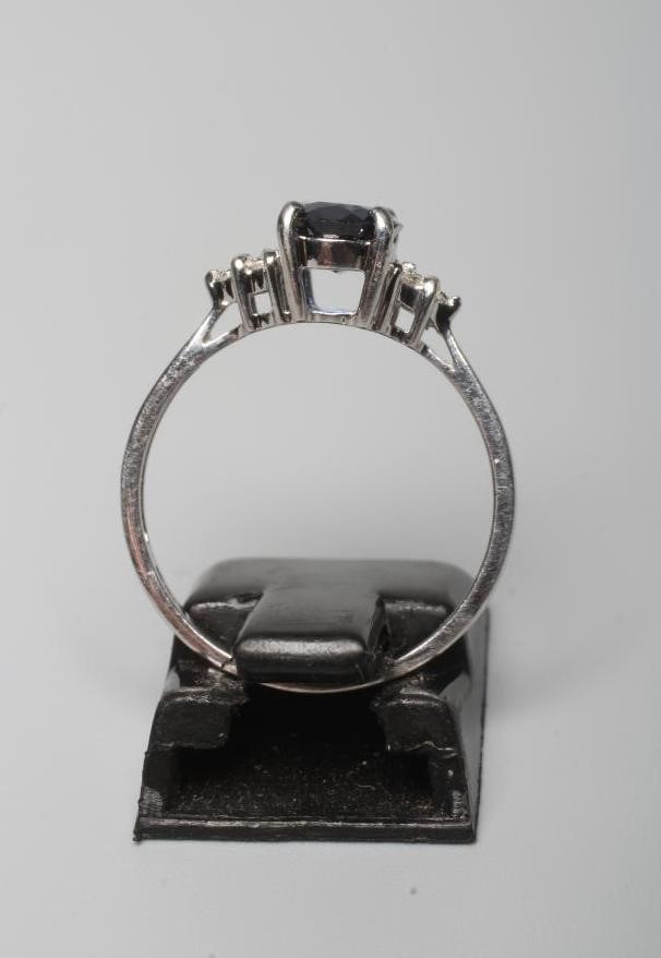 A SAPPHIRE RING, the oval facet cut stone claw set to shoulders each set with three small round Image