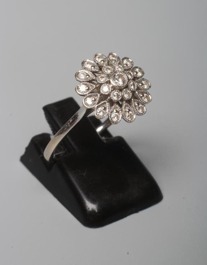 A DIAMOND CLUSTER RING, the flowerhead panel with numerous small stones pave set to a plain white Image