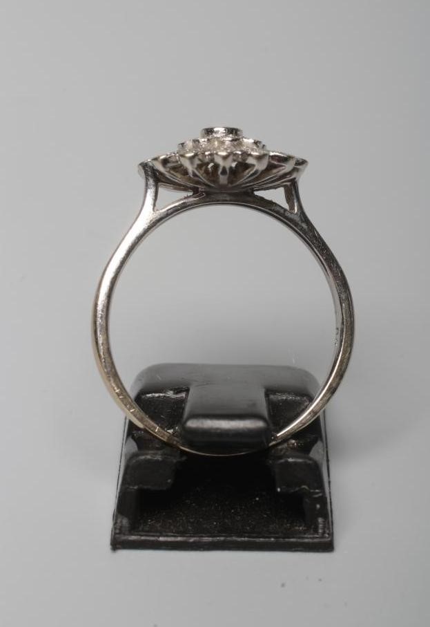 A DIAMOND CLUSTER RING, the flowerhead panel with numerous small stones pave set to a plain white Image