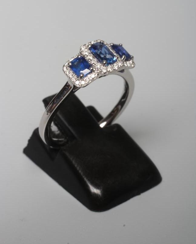 A SAPPHIRE AND DIAMOND DRESS RING, the three step cut sapphires claw and line set to borders of Image