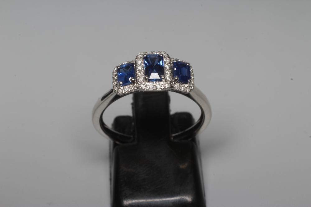A SAPPHIRE AND DIAMOND DRESS RING, the three step cut sapphires claw and line set to borders of Image