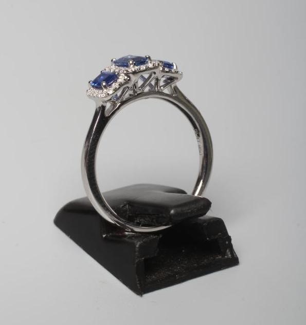 A SAPPHIRE AND DIAMOND DRESS RING, the three step cut sapphires claw and line set to borders of Image