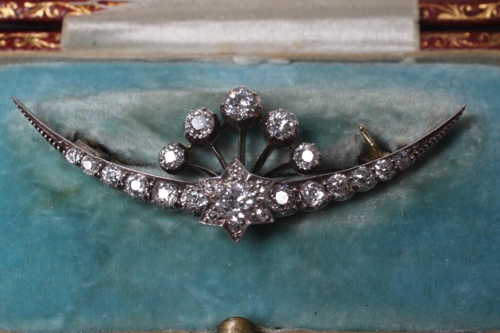 A DIAMOND CRESCENT BROOCH centred by a small star with a point set brilliant cut stone of Image